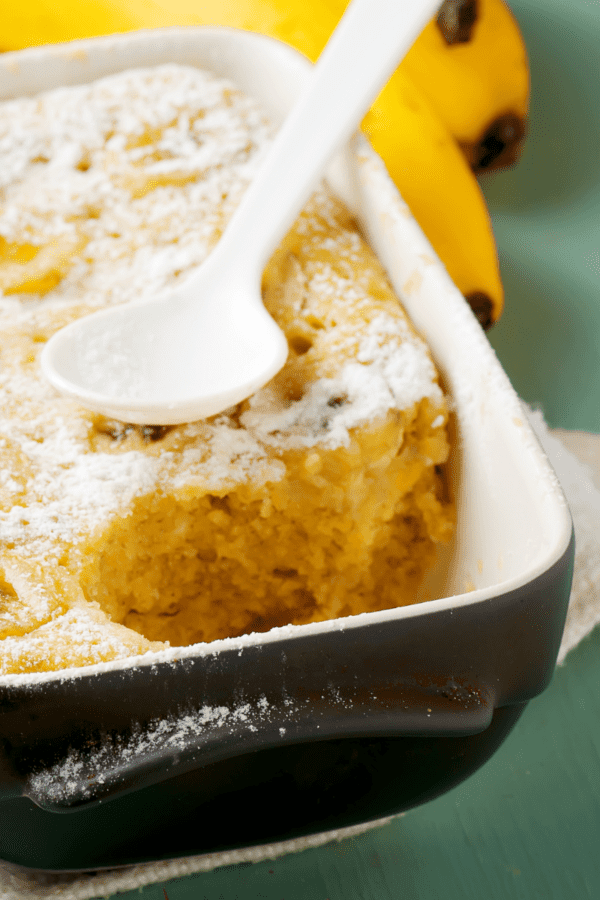 Banana Pudding Cake in a dark blue baking dish with a spoon on top