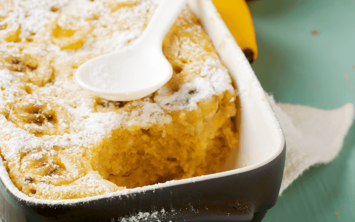 Banana Pudding Cake in a dark blue baking dish with a spoon on top