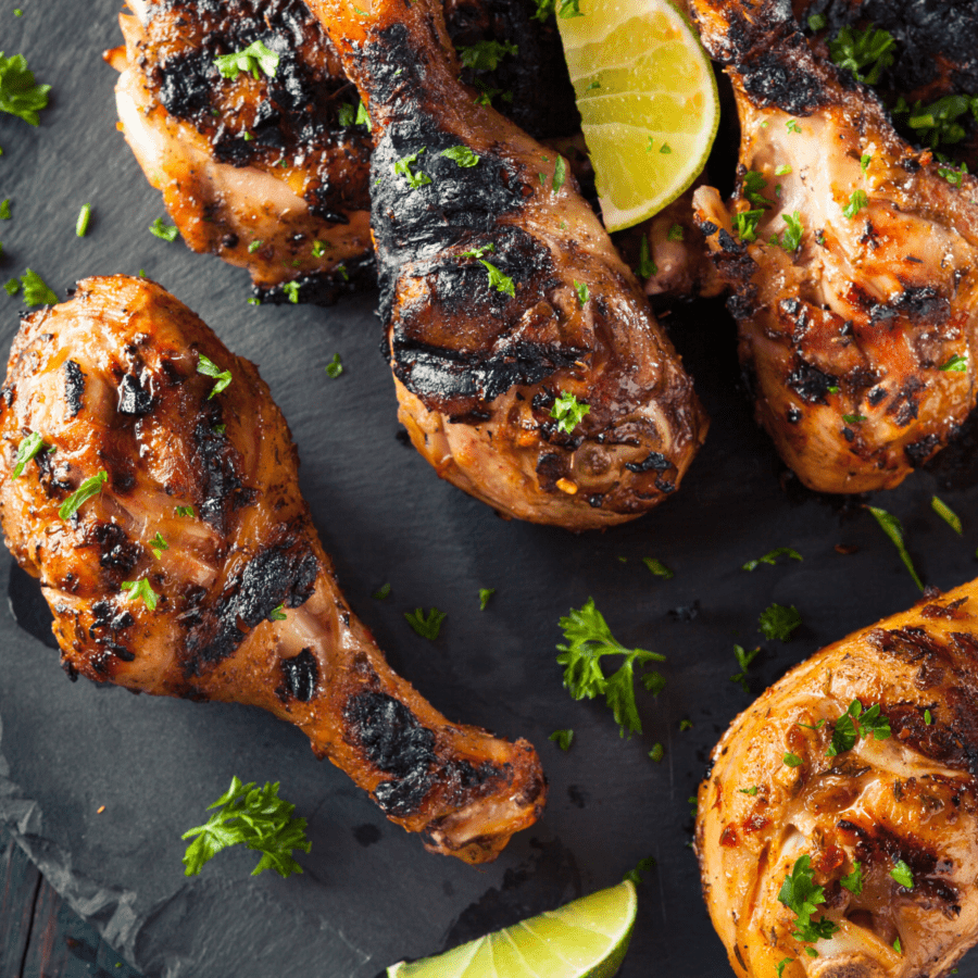 Blackened Chicken Drumsticks on a black background with cilantro and lime garnish