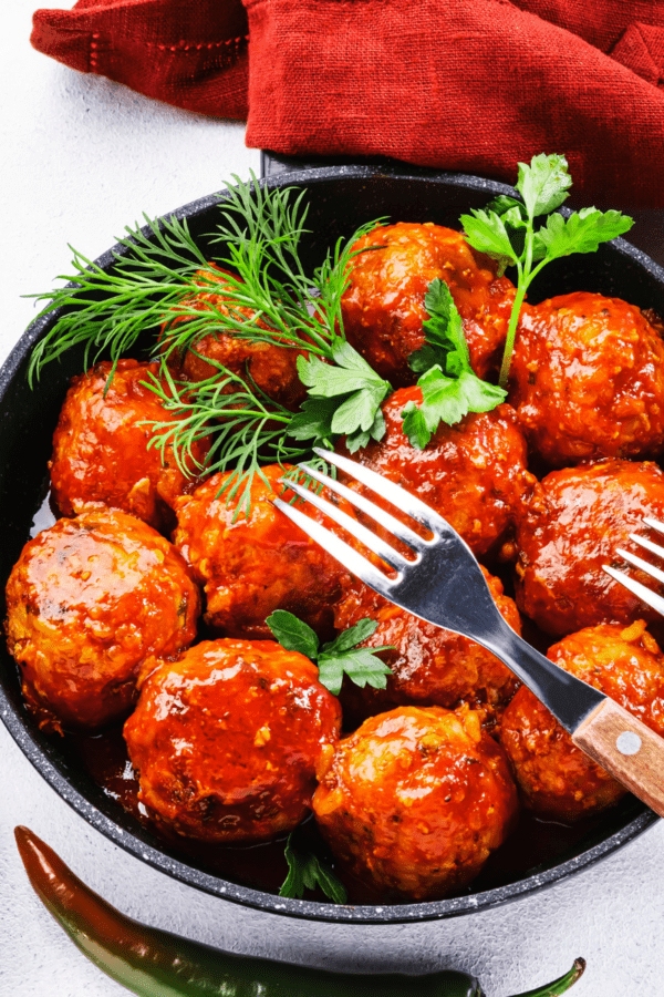 Buffalo Chicken Meatballs in a skillet with a fresh herb garnish