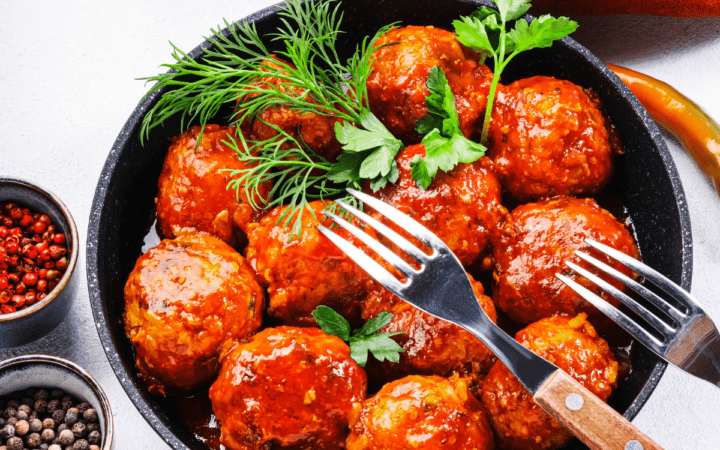 Buffalo Chicken Meatballs in a skillet with a fresh herb garnish