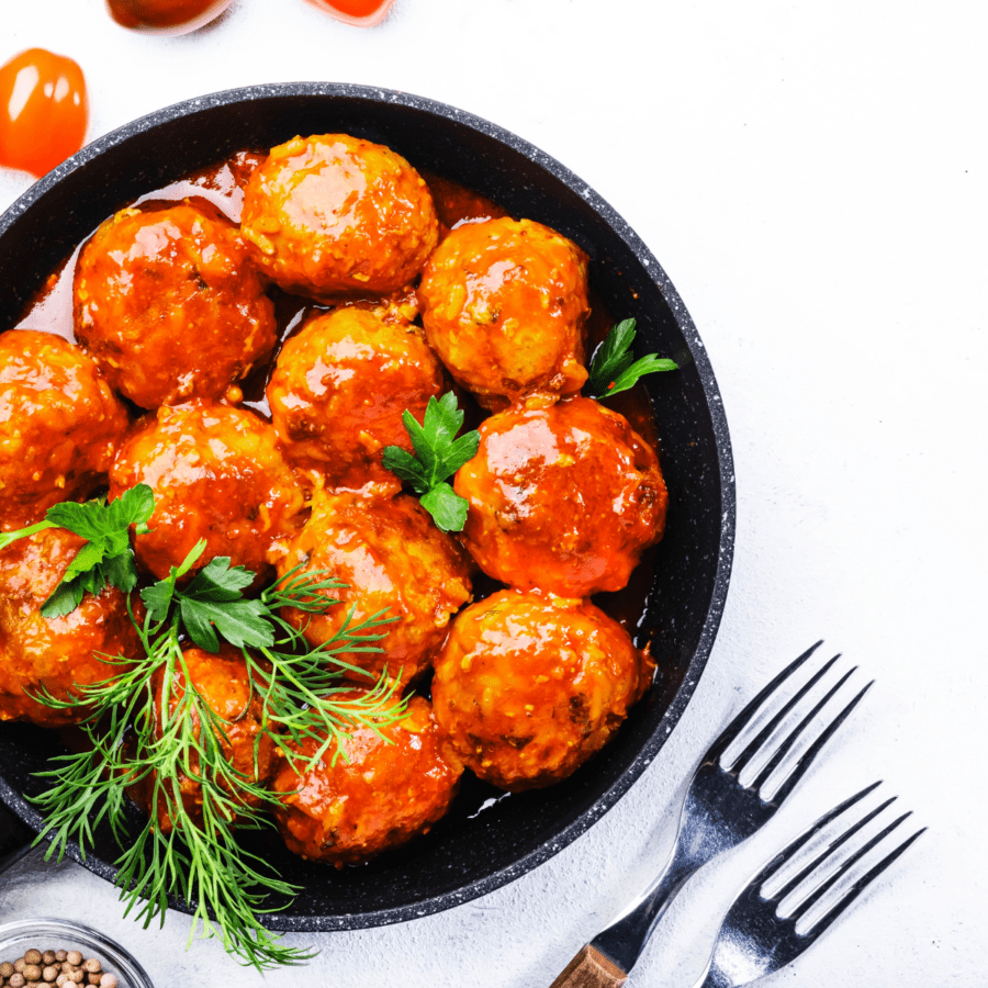 Overhead shot of buffalo chicken meatballs in a skillet with two forks sitting beside them