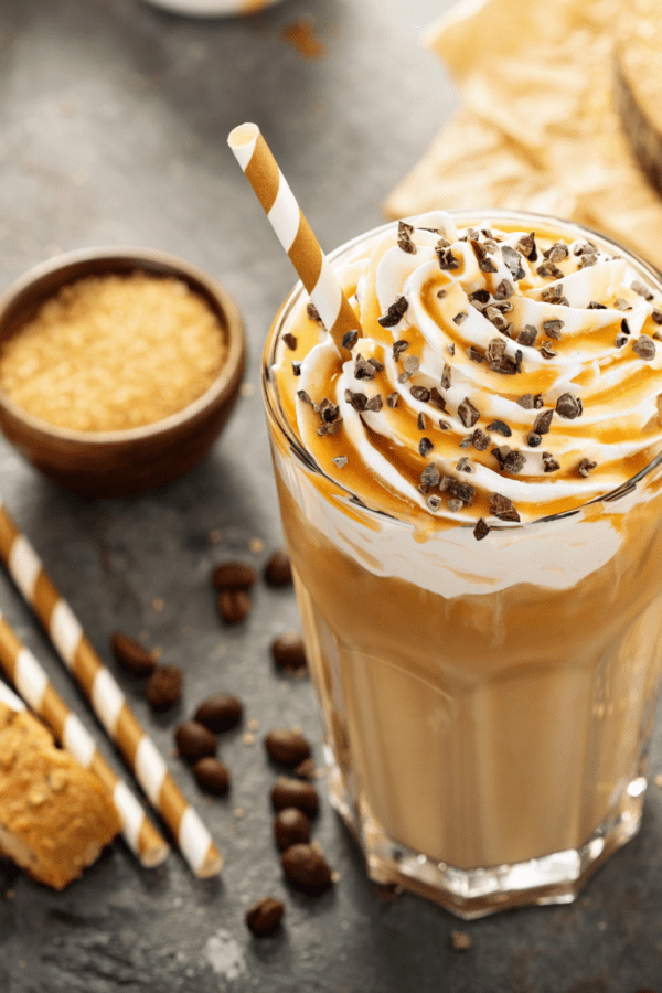 Overhead image of a caramel frappuccino starbucks copycat with biscotti and chocolate chips scattered around