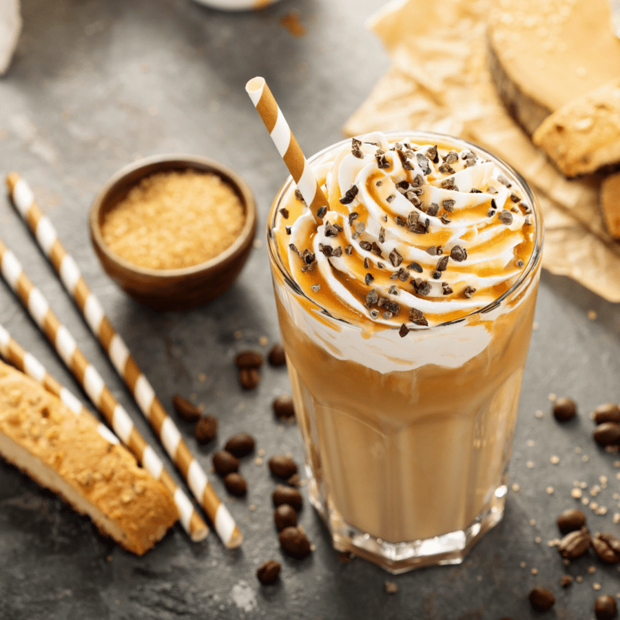 Overhead image of a caramel frappuccino starbucks copycat with biscotti and chocolate chips scattered around