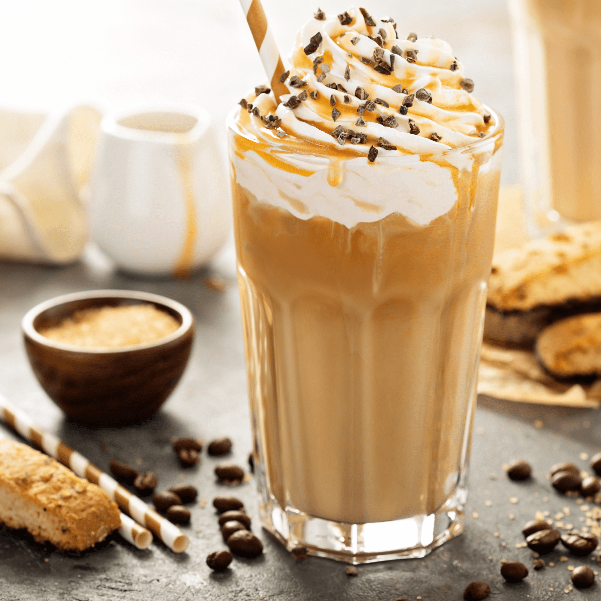 Caramel Frappuccino Starbucks Copycat in a glass with biscotti and chocolate chips surrounding it