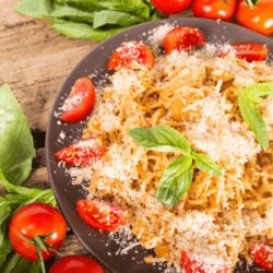 Overhead image of chicken spagehetti with rotel on a brown plate surrounded by tomatoes