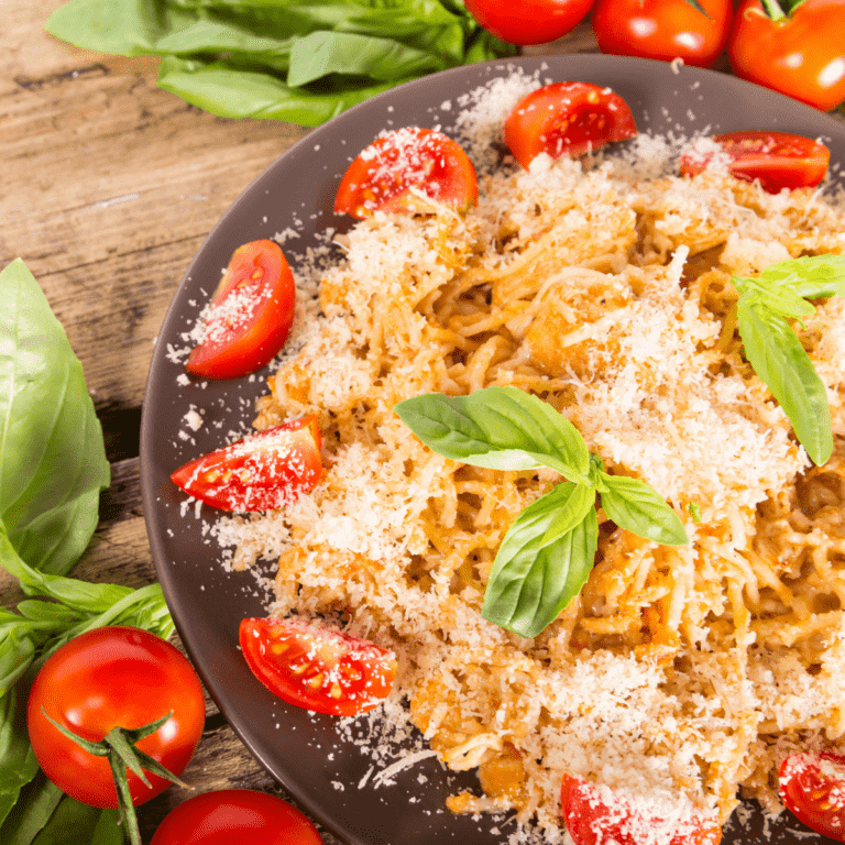 Overhead image of chicken spagehetti with rotel on a brown plate surrounded by tomatoes