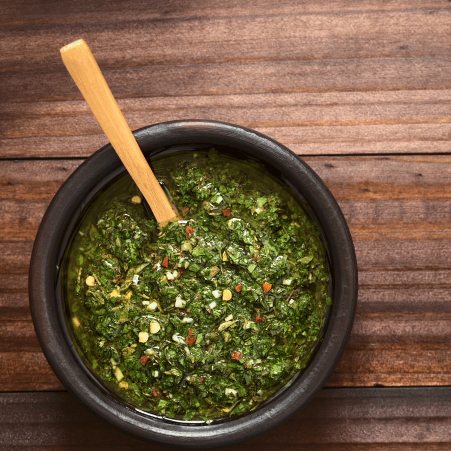 overhead image of cilantro chimichurri with a wooden serving spoon