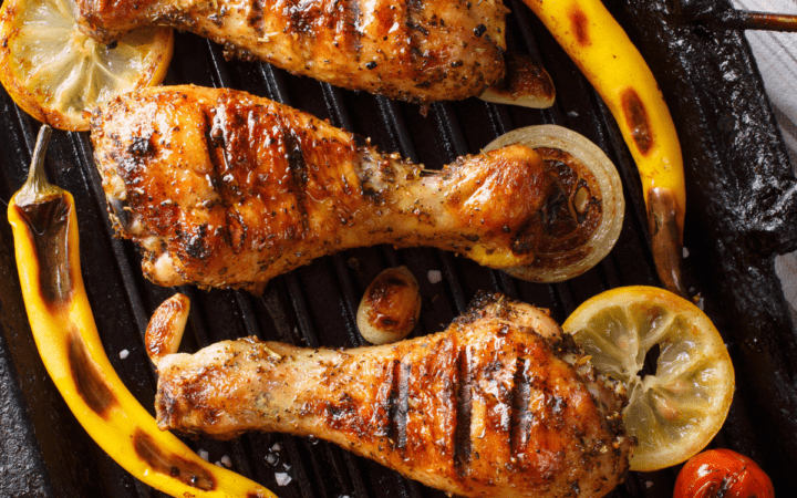 Lemon Pepper Chicken Drumsticks arranged next to grilled lemons and peppers