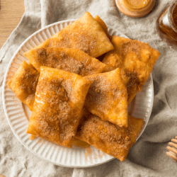 Overhead image of sopapillas on a white plate drizzled with honey