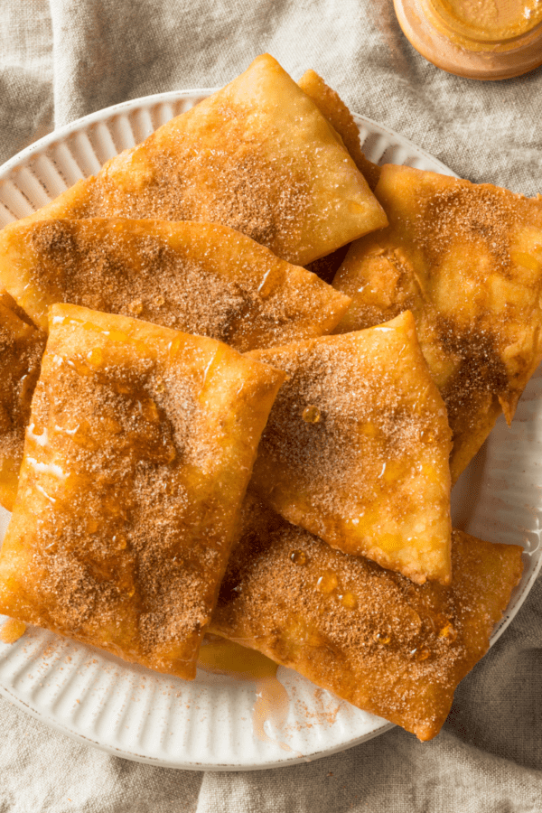 Overhead image of sopapillas on a white plate drizzled with honey
