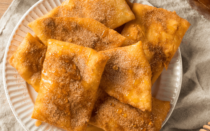Overhead image of sopapillas on a white plate drizzled with honey