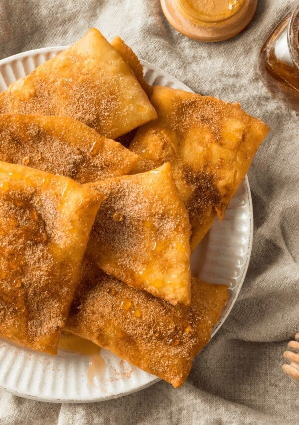 Overhead image of sopapillas on a white plate drizzled with honey