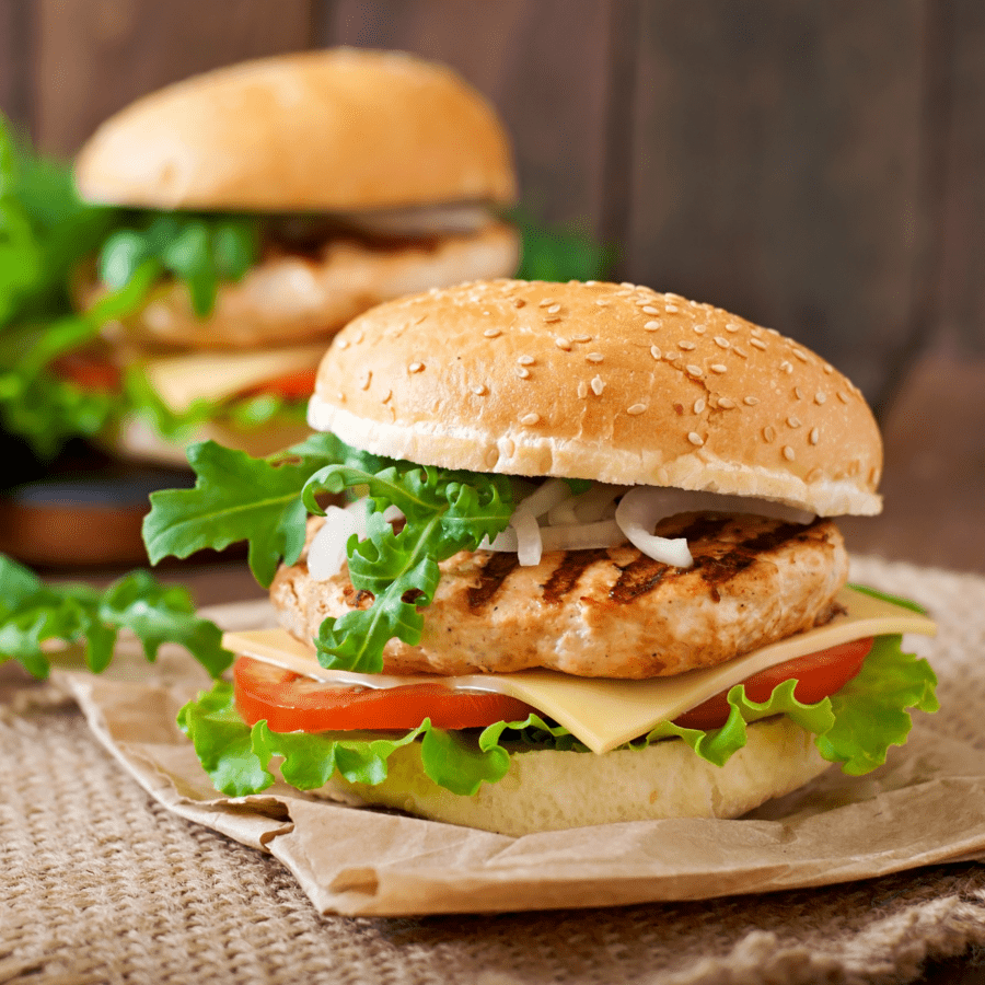 Two Chicken Burgers sitting on brown burlap