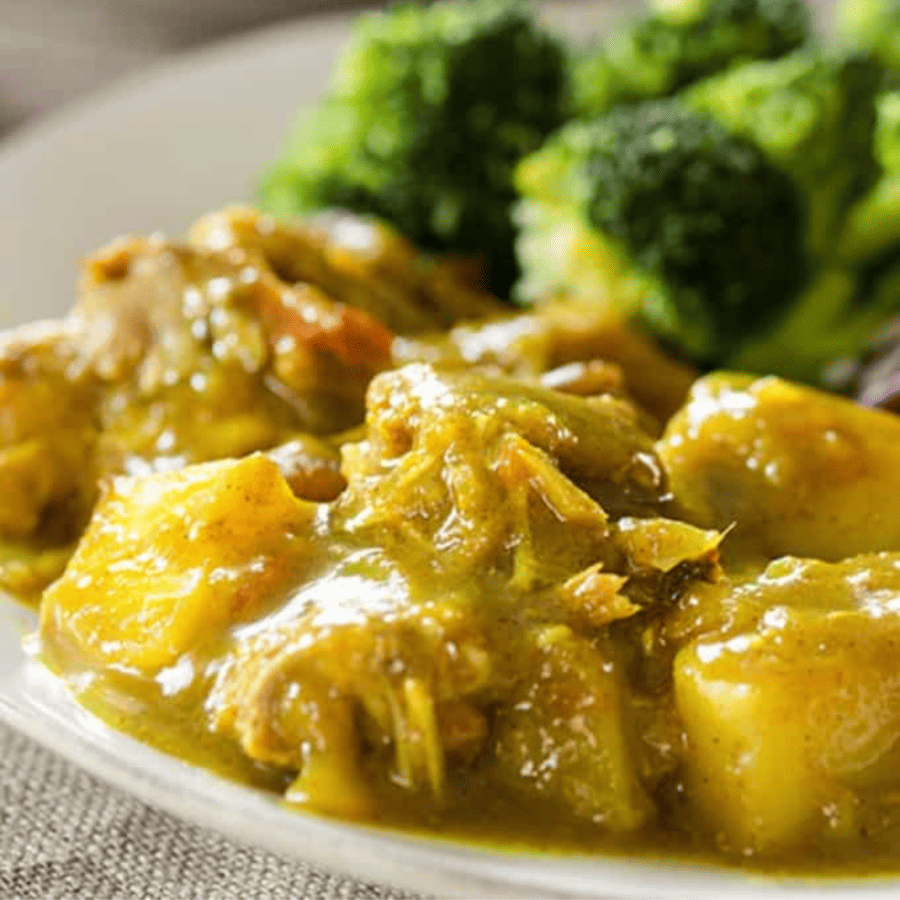 Close up image of Jamaican Chicken Curry on a plate with broccoli