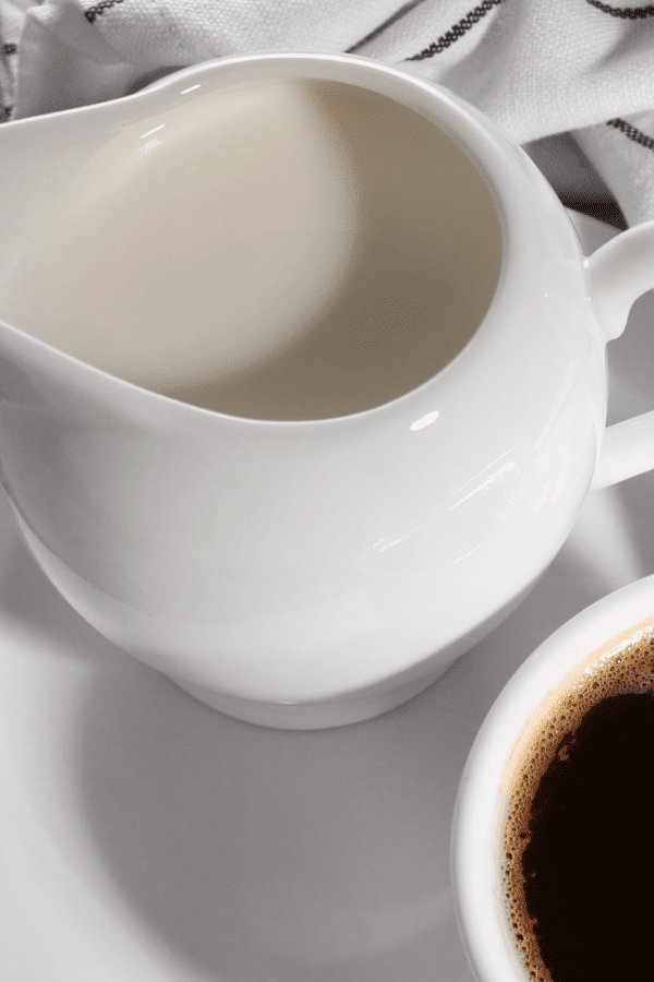 close up image of a jar of keto coffee creamer next to a cup of black coffee
