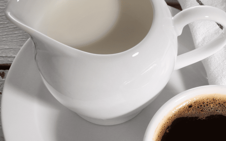 close up image of a jar of keto coffee creamer next to a cup of black coffee