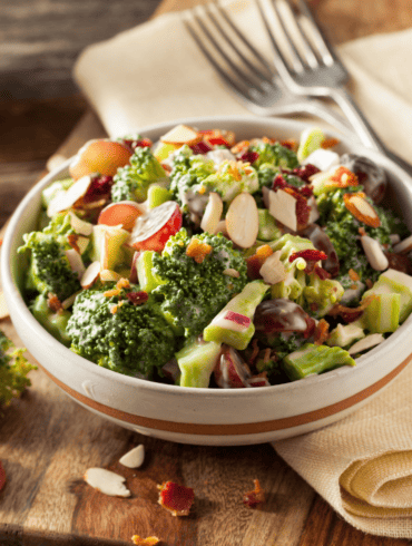 Broccoli Cauliflower Salad in a bowl on a wooden cutting board