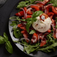 Close up of a burrata salad on a black plate