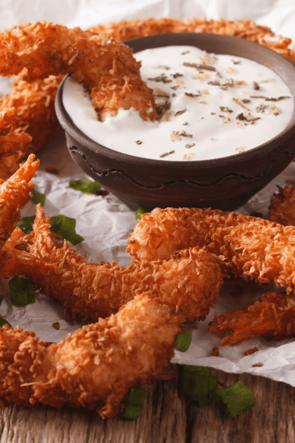 Coconut Shrimp on paper with a creamy dipping sauce