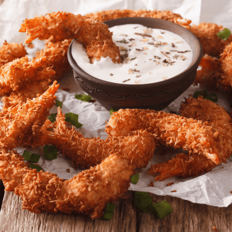 Coconut Shrimp on paper with a creamy dipping sauce