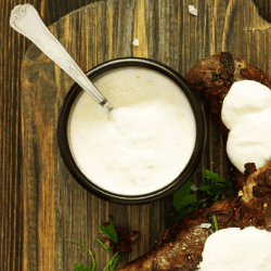 Overhead image of Alabama White Sauce in a black bowl next to bbq meat