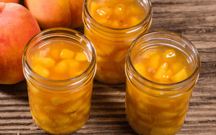 Three jars of peach pie filling in glass jars on a wooden table