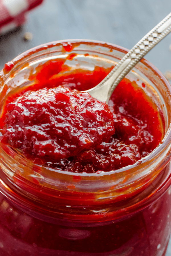 Close up of tomato jam in a glass jar with a spoon