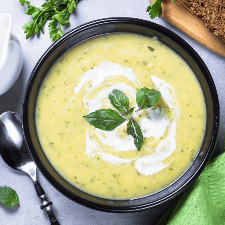 Overhead image of zucchini soup in a black bowl