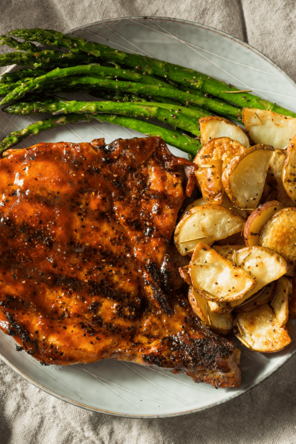 BBQ Pork Chops on a plate with potatoes and asparagus