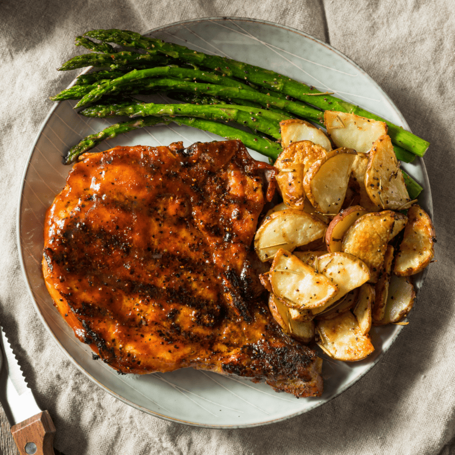 BBQ Pork Chops on a plate with potatoes and asparagus