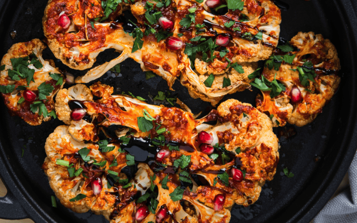 Closeup of cauliflower steaks topped with balsamic vinegar and herbs