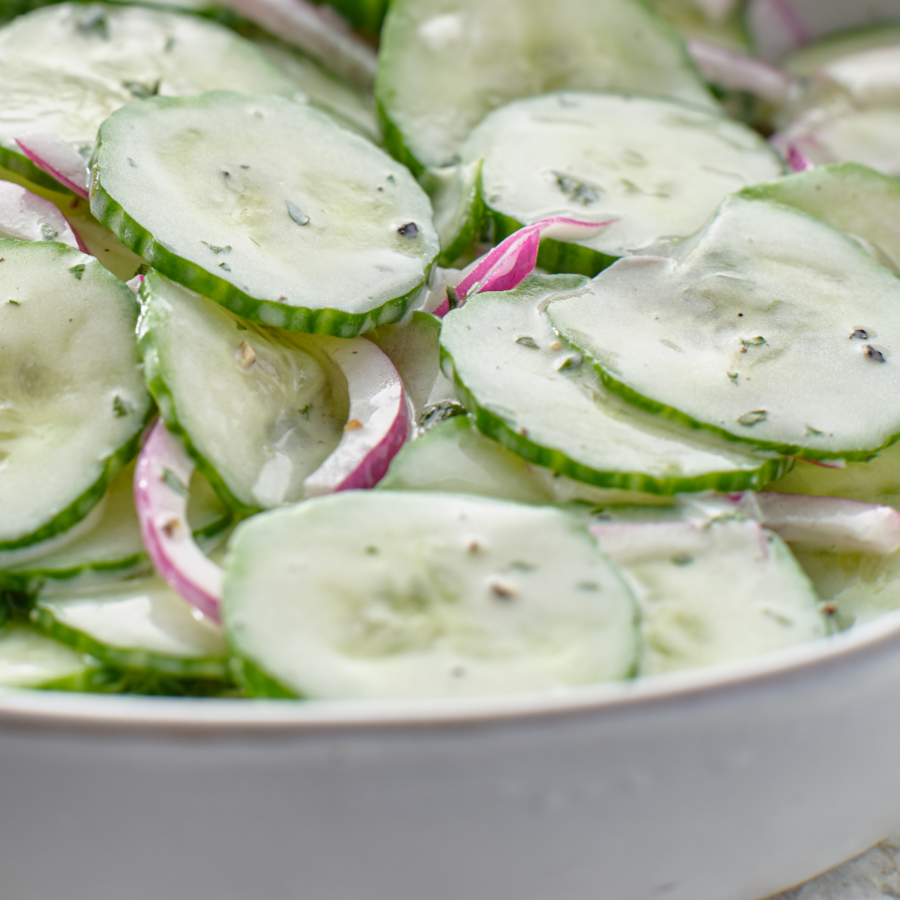 Close up image of creamy cucumber salad in a white bowl