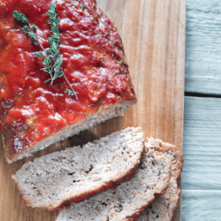 Italian meatloaf on a cutting board with slices taken out of the end