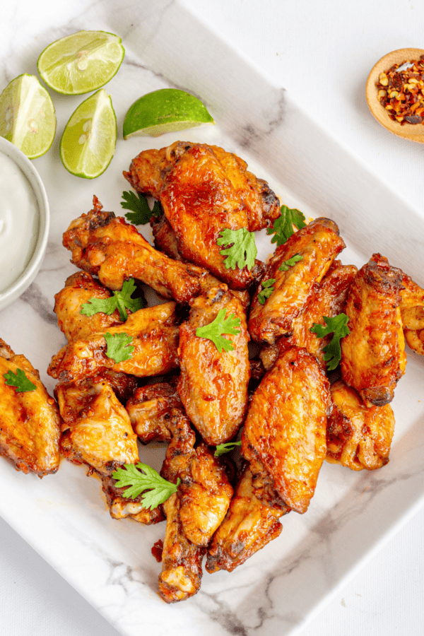 Baked chicken wings on a square white plate with dipping sauce