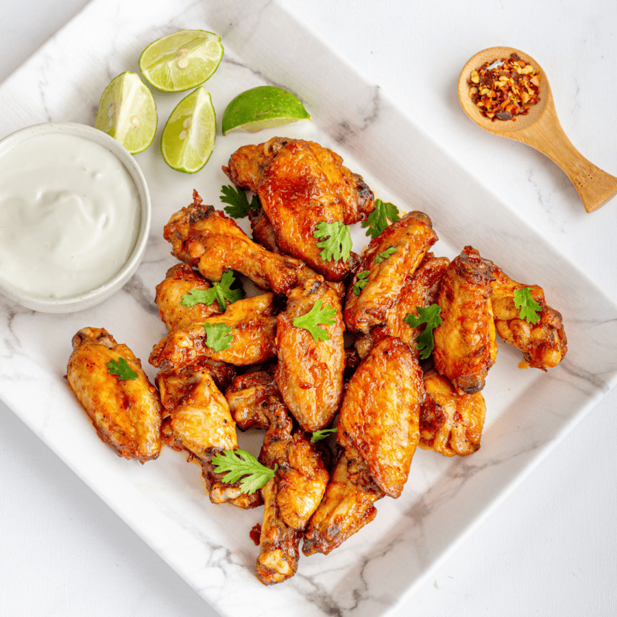 Baked chicken wings on a square white plate with dipping sauce