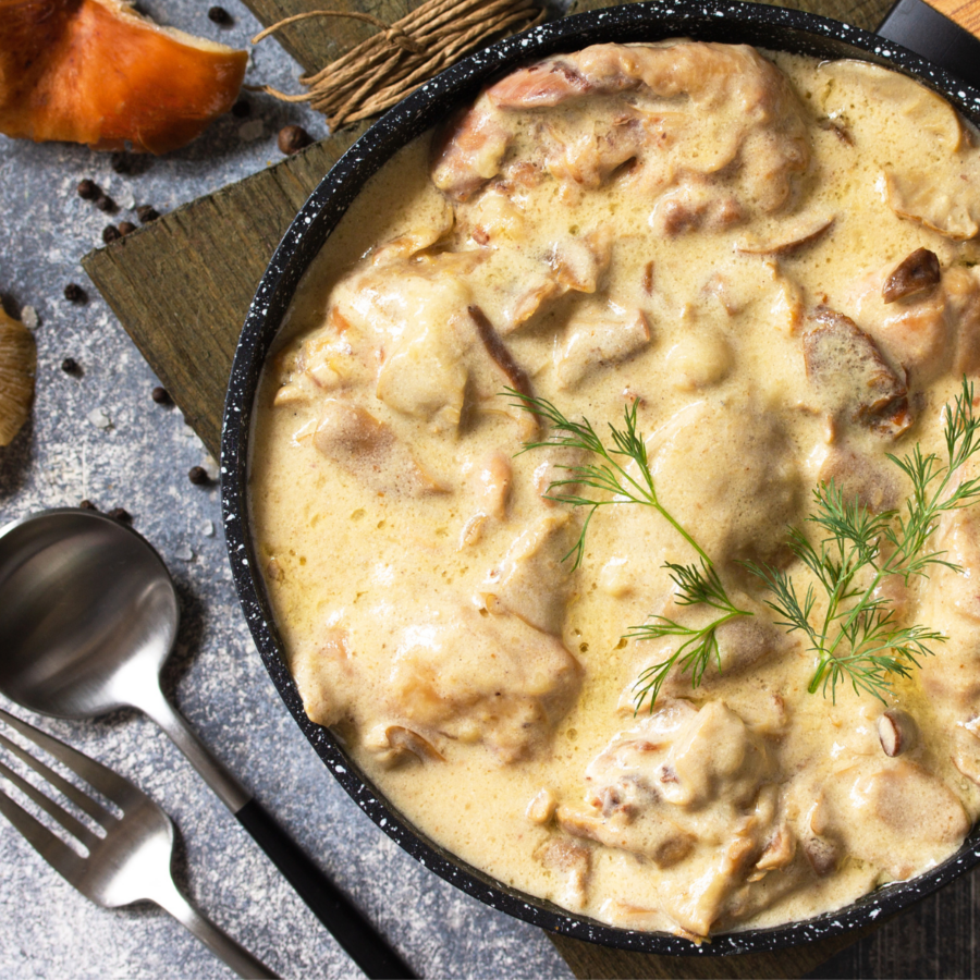 Close up of chicken stroganoff in a skillet with silverware sitting on the side