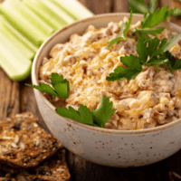 Reuben Dip in a cream colored bowl with rye bread and celery