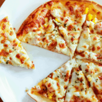 Overhead image of a tortilla pizza with a slice taken out of it