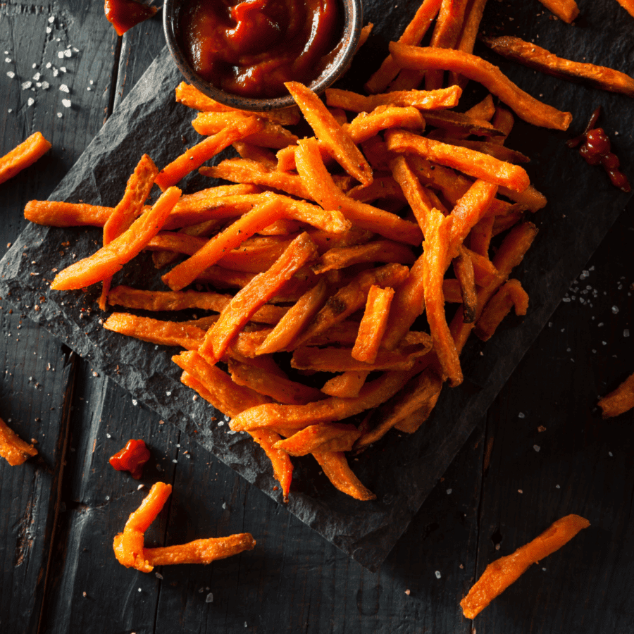 overhead image of sweet potato fries scattered on a black background