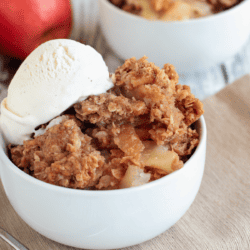 two white bowls of apple crumble with ice cream