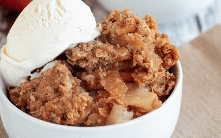 two white bowls of apple crumble with ice cream