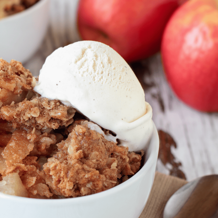 Closeup image of apple crumble in a white bowl with icecream