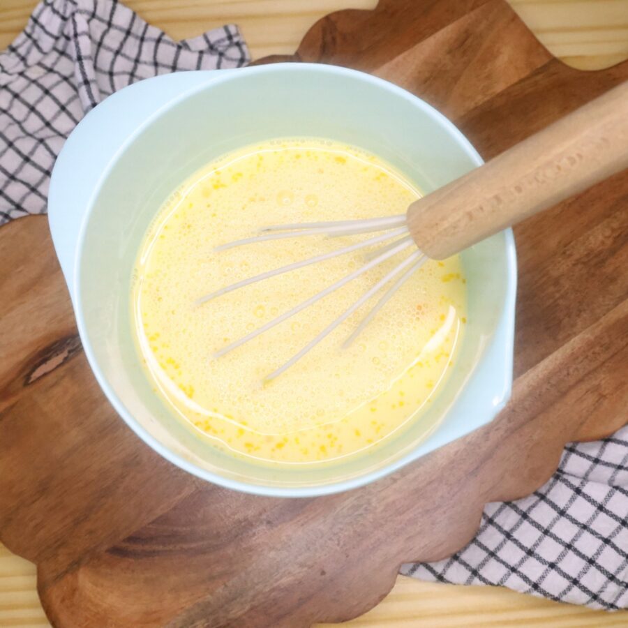 Wet ingredients for blueberry baked oatmeal in a bowl with a whisk
