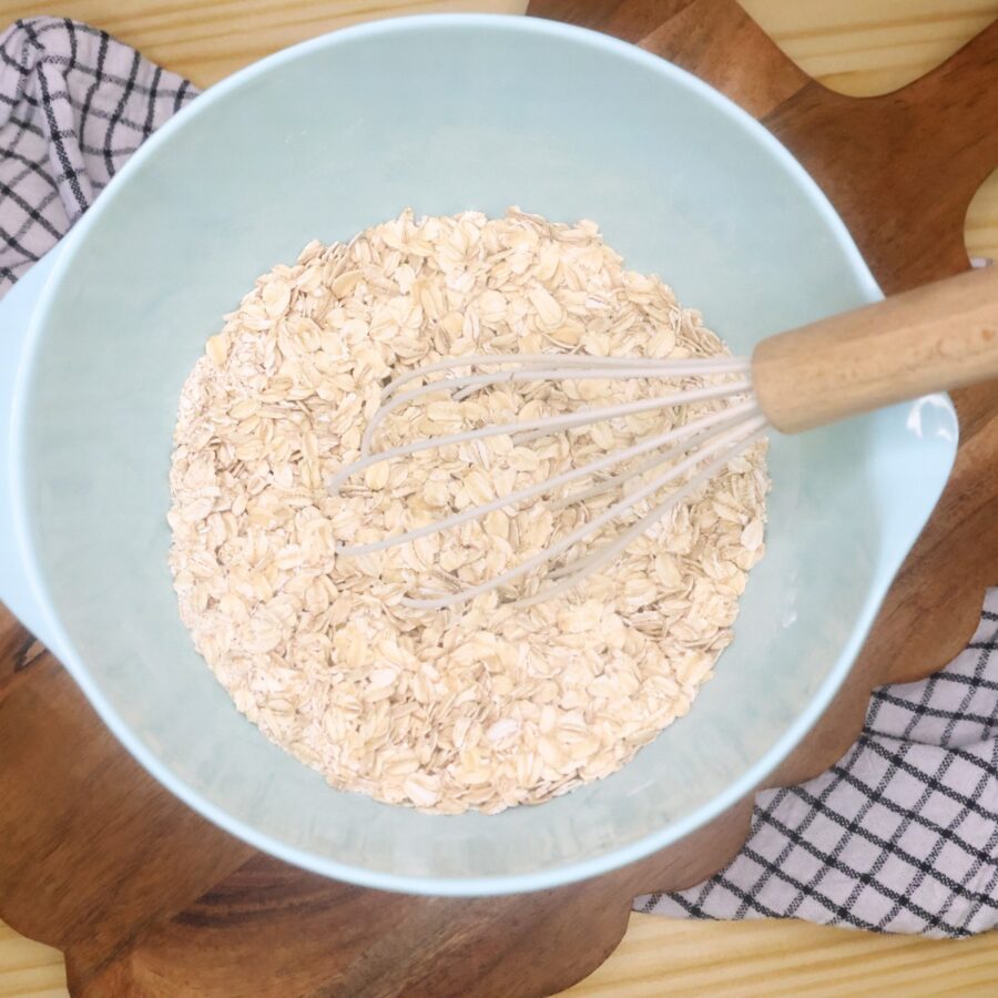 Dry ingredients for baked oatmeal in a bowl with a whisk