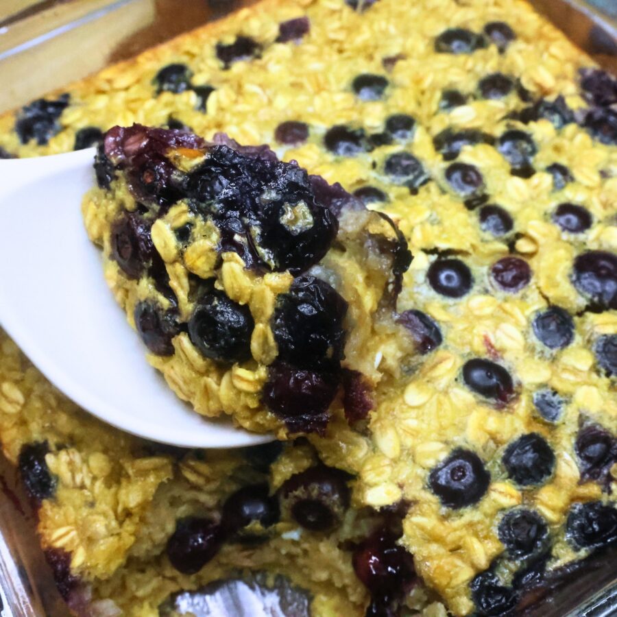 Close up image of baked oatmeal with blueberries being scooped with a spoon