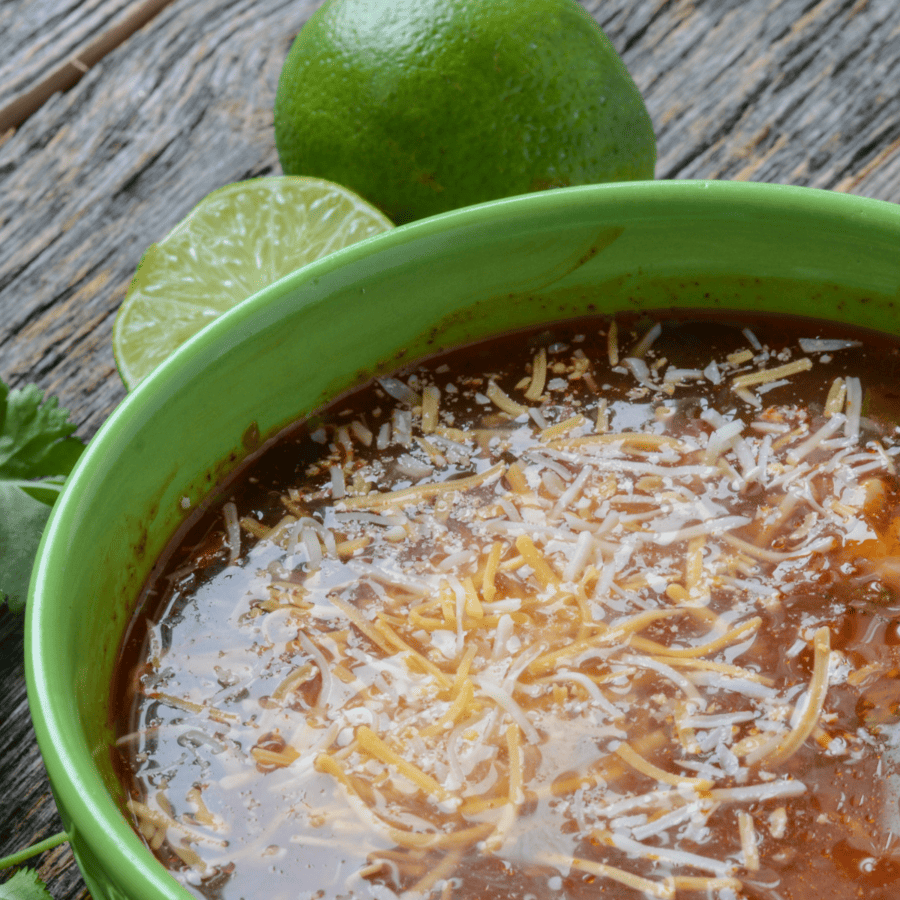 Close up image of Chicken Fajita Soup in a green bowl with limes next to it