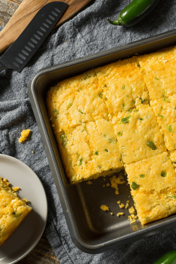 A pan of Mexican Cornbread with a plate of cornbread next to it