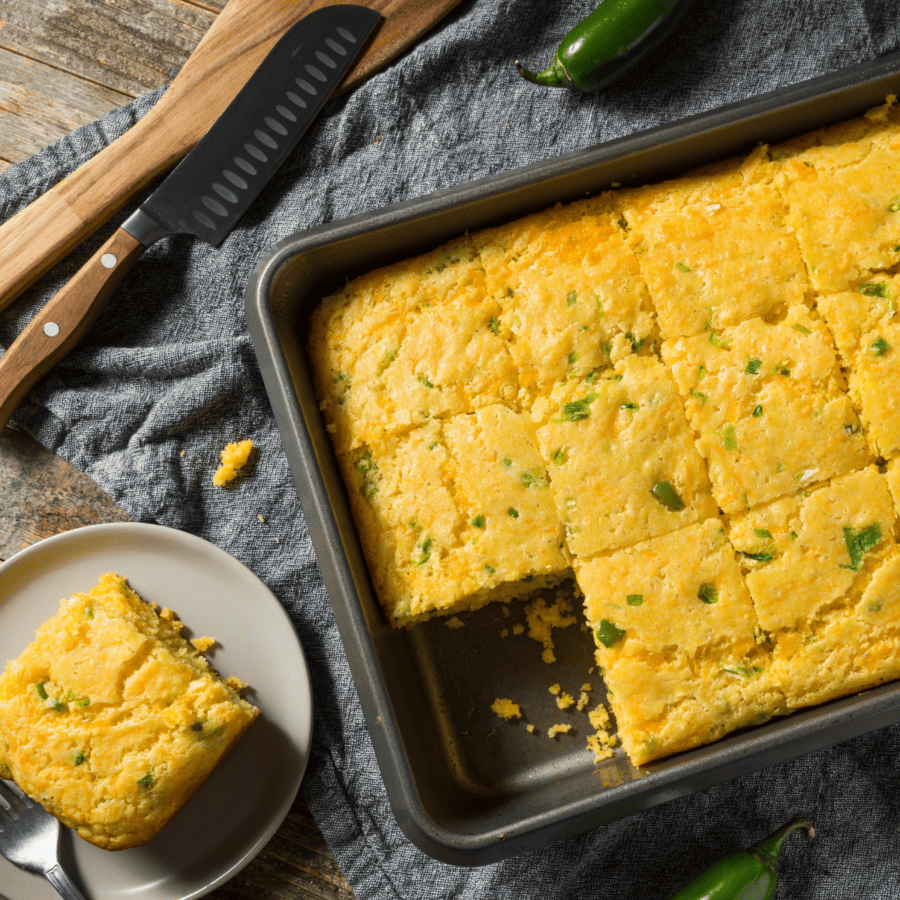 A pan of Mexican Cornbread with a plate of cornbread next to it