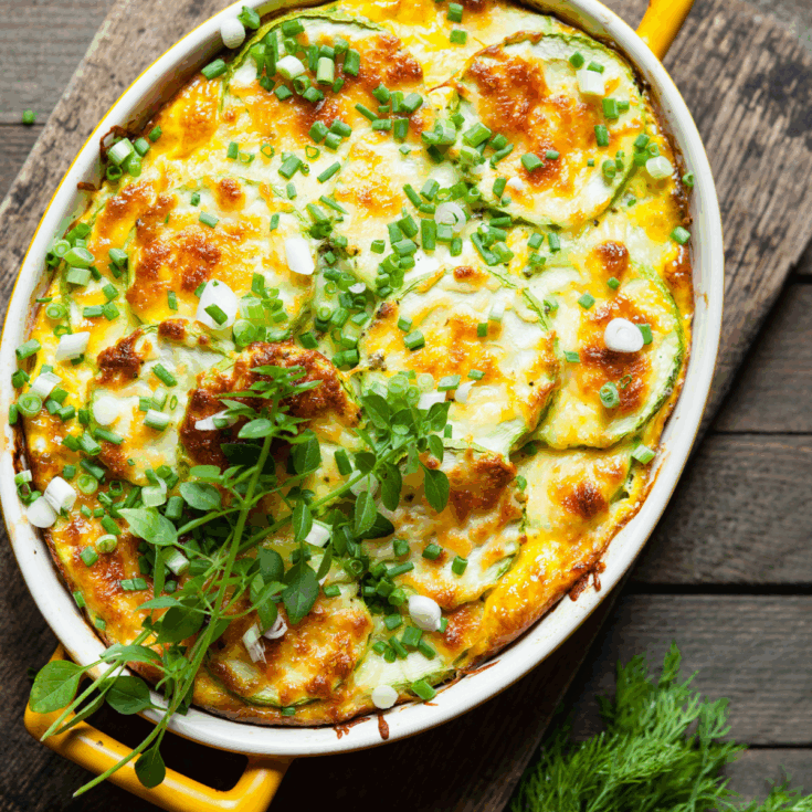 Overhead image of Zucchini Casserole in an oval baking dish on a cutting board